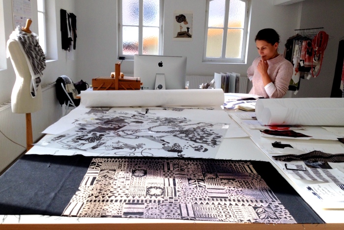 Lenka Kühnertova betrachtet an ihrem Zeichen- und Werktisch ihres Showrooms die Probedrucke ihrer Musterbücher